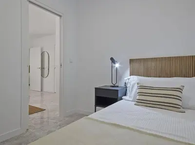 a white bedroom with a bed and a table and a mirror at Oasis Junto al Mar a 2 minutos de playa Sagunto A6 in Puerto de Sagunto