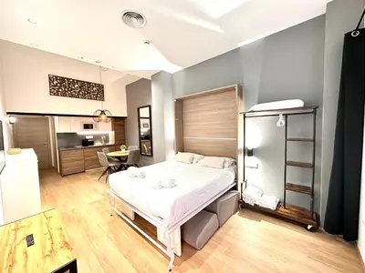 a bedroom with a large bed and a kitchen at Place Your Place SUITES Benimaclet in Valencia