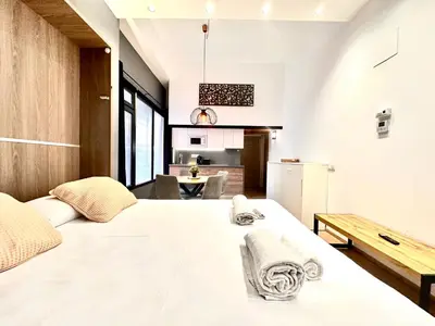 a bedroom with a large white bed and a kitchen at Place Your Place SUITES Benimaclet in Valencia