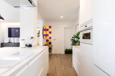 a white kitchen with white cabinets and wooden floors at UrbanNest Apartment in Valencia