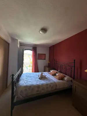 a bedroom with a bed with a red wall at Port Saplaya 2 habitaciones Valencia in Port Saplaya