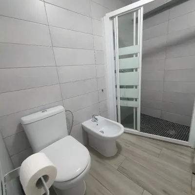 a white bathroom with a toilet and a shower at Apartamento Berenguer in Cullera