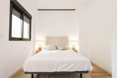 a white bedroom with a large bed with white sheets at Roca 26 in Valencia