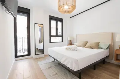 a bedroom with a large white bed and two windows at Roca 26 in Valencia