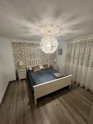 a bedroom with a large bed and a chandelier at Departamento en Torrent in Torrent