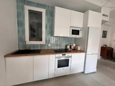 a kitchen with white cabinets and a sink and a refrigerator at Romantic Apartment in Cabanyal by Virkin Suites in Valencia