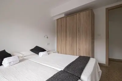 a bedroom with a white bed and a wooden cabinet at GuestReady - Valencia Bliss near Malvarrosa Beach in Valencia