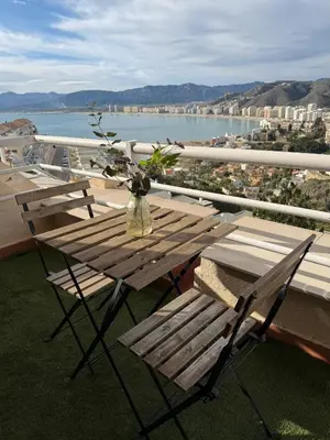 a wooden table with a vase of flowers on a balcony at Apartamento con increíbles vistas a la bahía de Cullera in Faro de Cullera