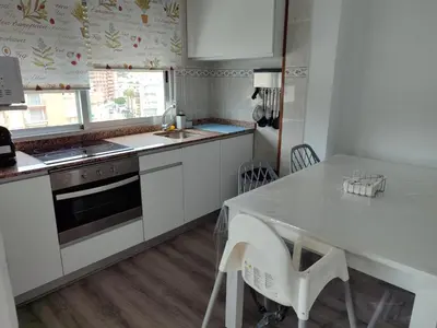 a kitchen with white cabinets and a table with chairs at Seaviews Los Olivos in Cullera