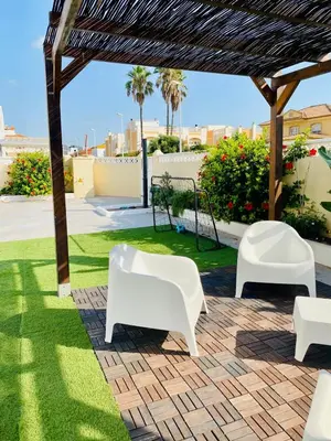 a patio with two white chairs and grass at El Riuet-Chalet apartamento a 1 minuto de la playa, Cullera in Cullera