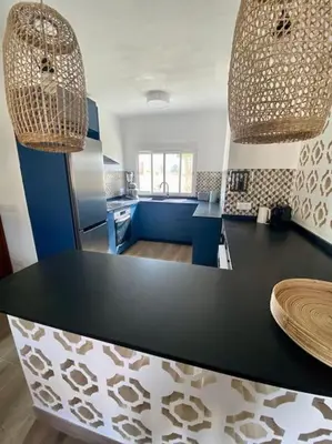 a kitchen with a black and white counter top at El Riuet-Chalet apartamento a 1 minuto de la playa, Cullera in Cullera