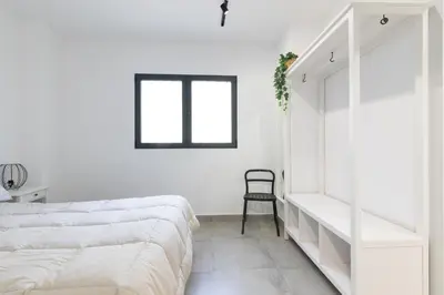 a white bedroom with a bed and a chair at NEW BEACH Flats valencia 1 in Valencia