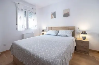 a white bedroom with a large bed and a window at Piso Reformado Cerca de la Playa y de Valencia Ciudad en el Barrio de San Antonio in Cullera