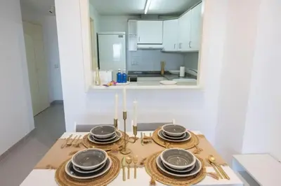 a table with plates and utensils on it in a kitchen at Espacio2,1a línea,jacuzzi,piscina in Cullera