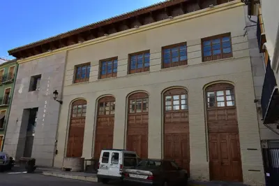 a building with brown doors and a car parked in front at Alojamientos Segóbriga Rural (Montaña) in Segorbe