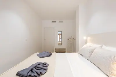 a white bedroom with a bed with a towel on it at Nuevo piso cerca de universidad y playa in Valencia