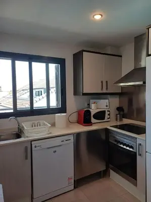 a kitchen with a sink and a stove top oven at Amplio duplex en la playa con piscina in Almarda