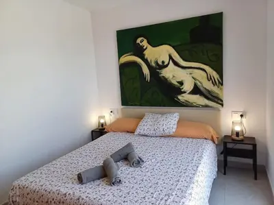 a bedroom with a bed and a painting on the wall at Amplio duplex en la playa con piscina in Almarda