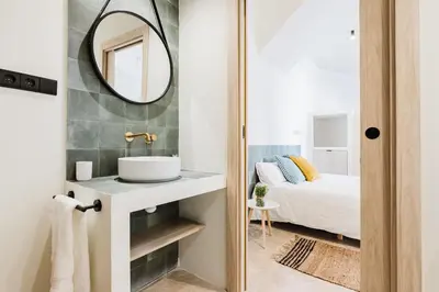 a bathroom with a sink and a mirror next to a bed at Loft Viñas in Valencia