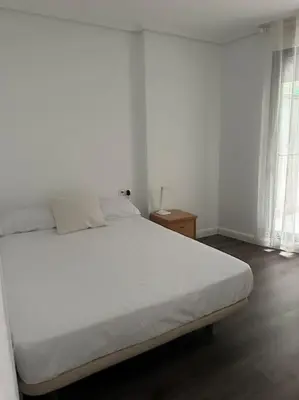 a white bed in a white room with a window at Apartamento playa Veramar patacona in Valencia