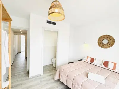 a white bedroom with a pink bed and a mirror at NUEVO, a 90 metros de la playa y con vistas al mar in Cullera