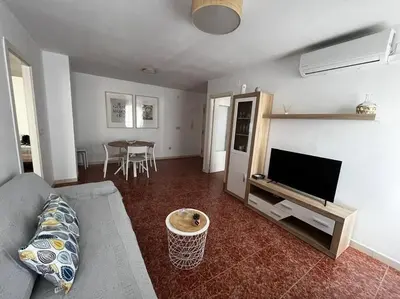 a living room with a couch and a tv and a table at Tu Refugio con Vistas al Mar in Puebla de Farnals
