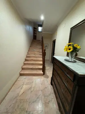 a hallway with stairs and a vase of flowers on a dresser at Casa Rural Piker in Bolbaite