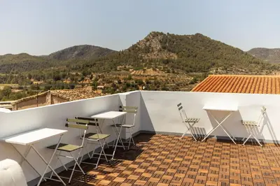 a room with tables and chairs on a roof with mountains at Casa rural las golondrinas in Quesa