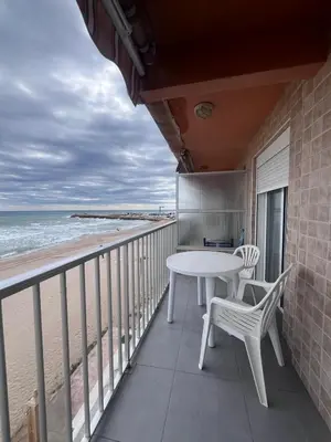a balcony with a table and chairs and the beach at 1ª Linea de Mar 4pax Valencia 15 min in El Perellonet