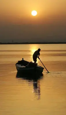 a man rowing a boat in the water at sunset at 1ª Linea de Mar 4pax Valencia 15 min in El Perellonet