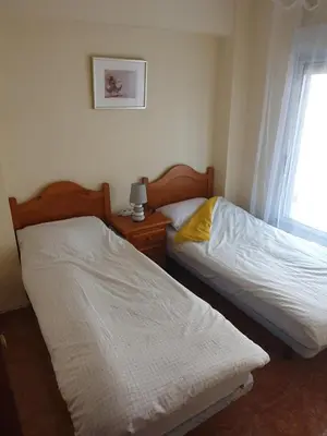 two beds in a small room with a window at Cosy apartment near the beach in Cullera