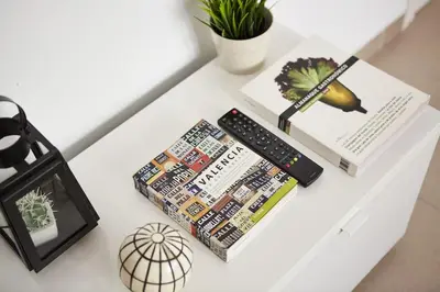 a table with a remote control and books on it at Amplio y cómodo apartamento en el centro in Valencia