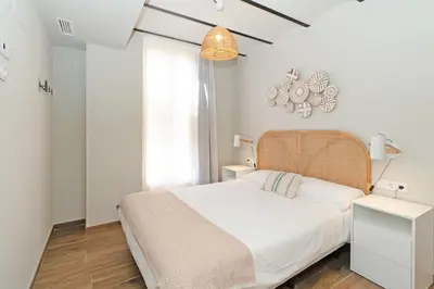 a white bedroom with a bed and a window at Maritime Apartamentos Puerto in Valencia