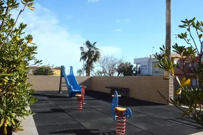 a playground with blue and red swings in a backyard at Apartamento a 60 metros de la Playa in Playa de Mar