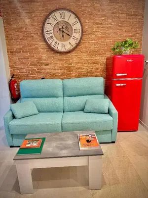 a living room with a blue couch and a clock at Céntrico, coqueto y vintage in Valencia