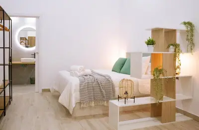 a white bedroom with a bed and a mirror at La Brisa Lofts in Valencia