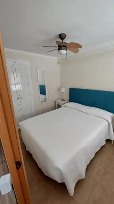 a bedroom with a large white bed with a ceiling fan at Playa, relax y parking público cerca - Ideal parejas in Cullera