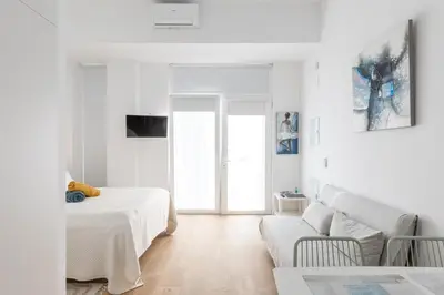 a white living room with a bed and a couch at Estudio Marina Ivana in Valencia