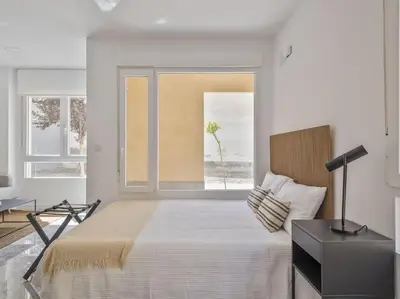 a white bedroom with a large bed and a window at Loft Temporal a 2 min de Playa de Sagunto A1 in Puerto de Sagunto