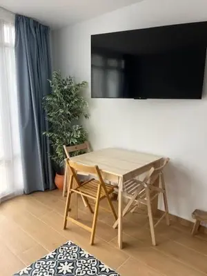 a wooden table and chairs with a television on a wall at ALZIRA BONITA AMPLIO APARTAMENTO 25 CON HABiTACION Y VISTAS AL RIO JUCAR in Alzira