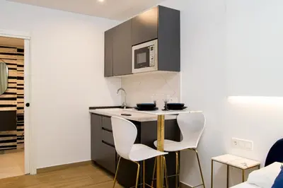 a small kitchen with two white chairs and a counter at Forata lofts in Valencia