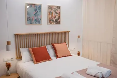 a bedroom with a bed with white sheets and orange pillows at Lofts plaza JM Orense B in Valencia
