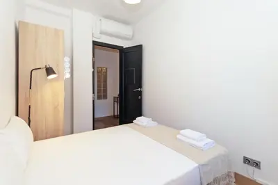 a white bedroom with two beds and a hallway at GuestReady - Valencia's Sushine Terrace in Valencia