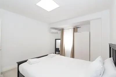 a white bedroom with a bed and a mirror at GuestReady - A lovely gem near La Malvarrosa beach in Valencia