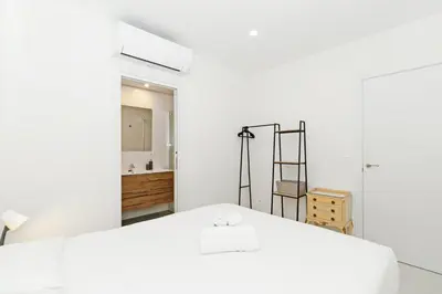 a white bedroom with a bed and a bathroom at GuestReady - Piso moderno con vistas a la Marina in Valencia