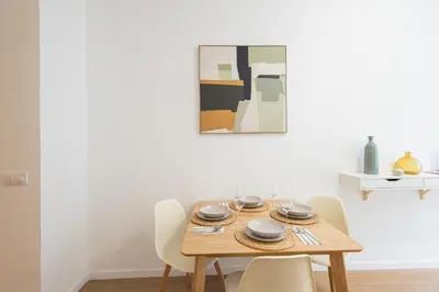 a dining room table with chairs and a painting on the wall at FLORIT FLATS - The Maritim Metro Station Suites in Valencia