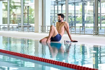 a man sitting on the edge of a swimming pool at Calderona Wellness in Bétera