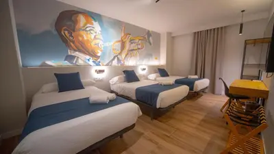a room with two beds and a painting on the wall at Hotel Sleep Turia music & art in Lliria