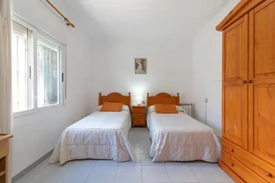 two beds in a room with white walls at Global Vacacional, Apartamento en Puerto de Sagunto in Puerto de Sagunto