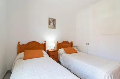 two beds in a room with white walls at Global Vacacional, Apartamento en Puerto de Sagunto in Puerto de Sagunto